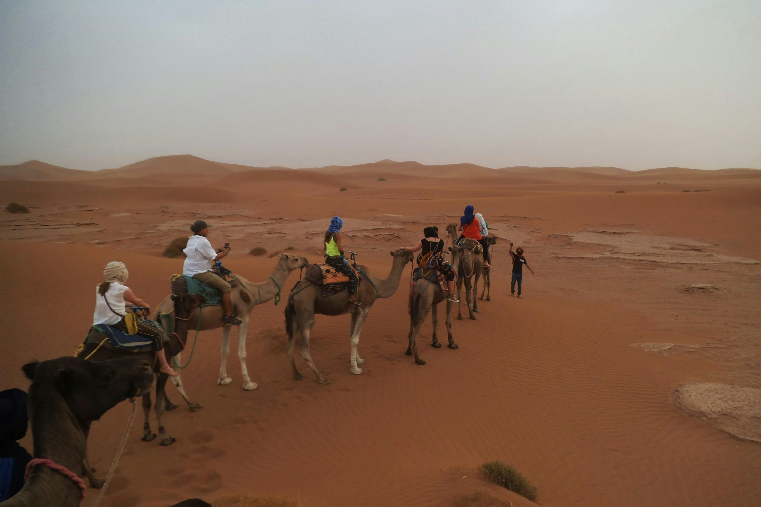 Famille voyageant à dos de dromadaires dans le désert du Maroc, au coucher du soleil, symbole d’aventure et de découverte en famille.